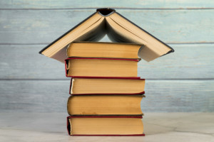 house-structure-made-with-vintage-books-against-wooden-wall_23-2148038707